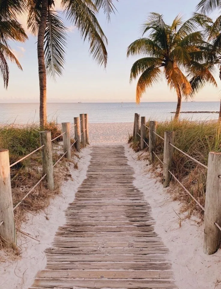 A beach boardwalk leading toward the ocean at sunset